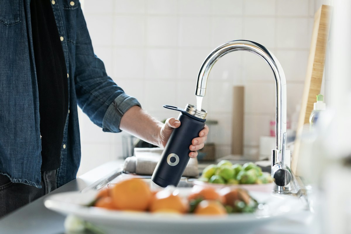 A hand holding a stainless steel faucet