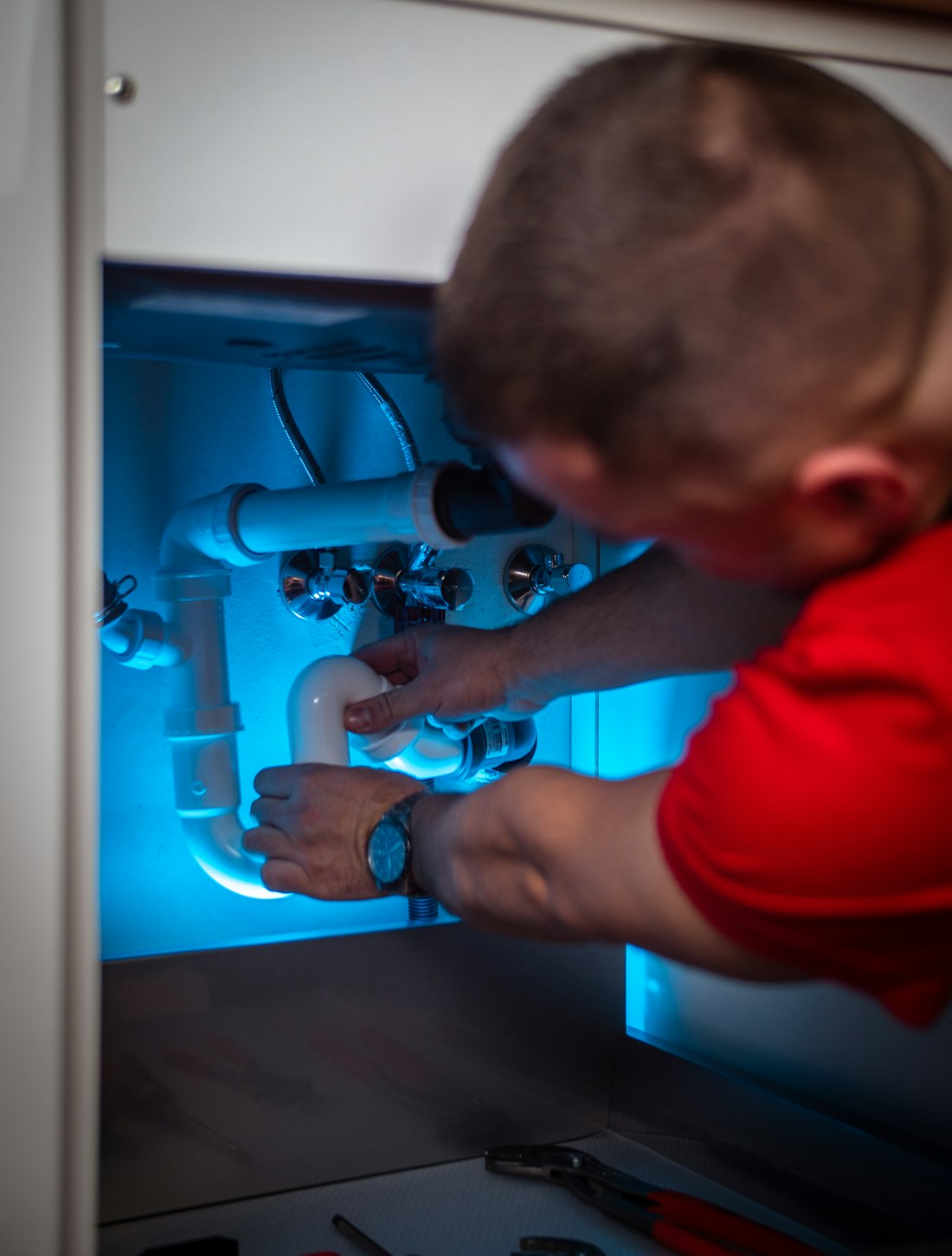 Plumber working on pipework inside a cabinet