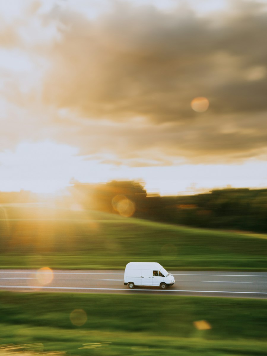 A white service van driving along a country road