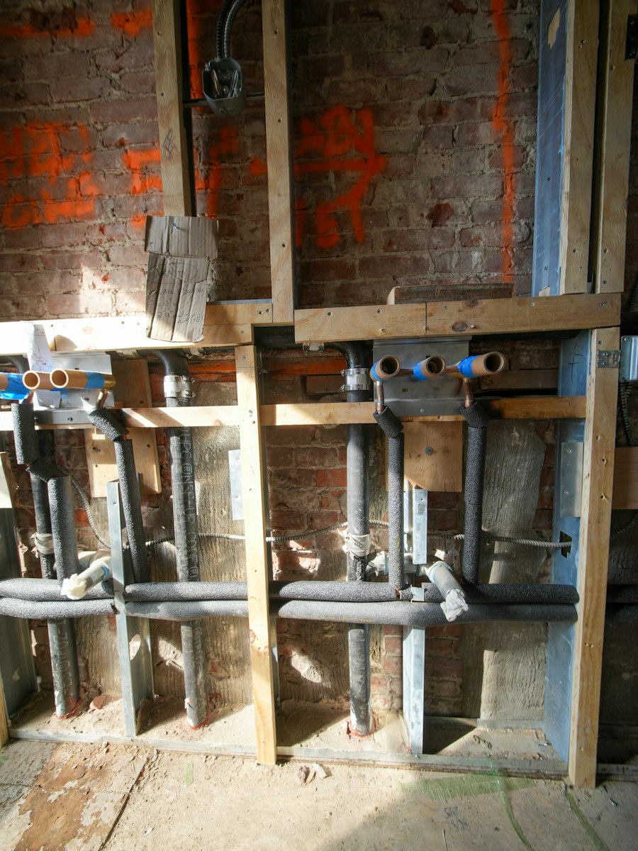 Exposed plumbing pipework inside an open wall